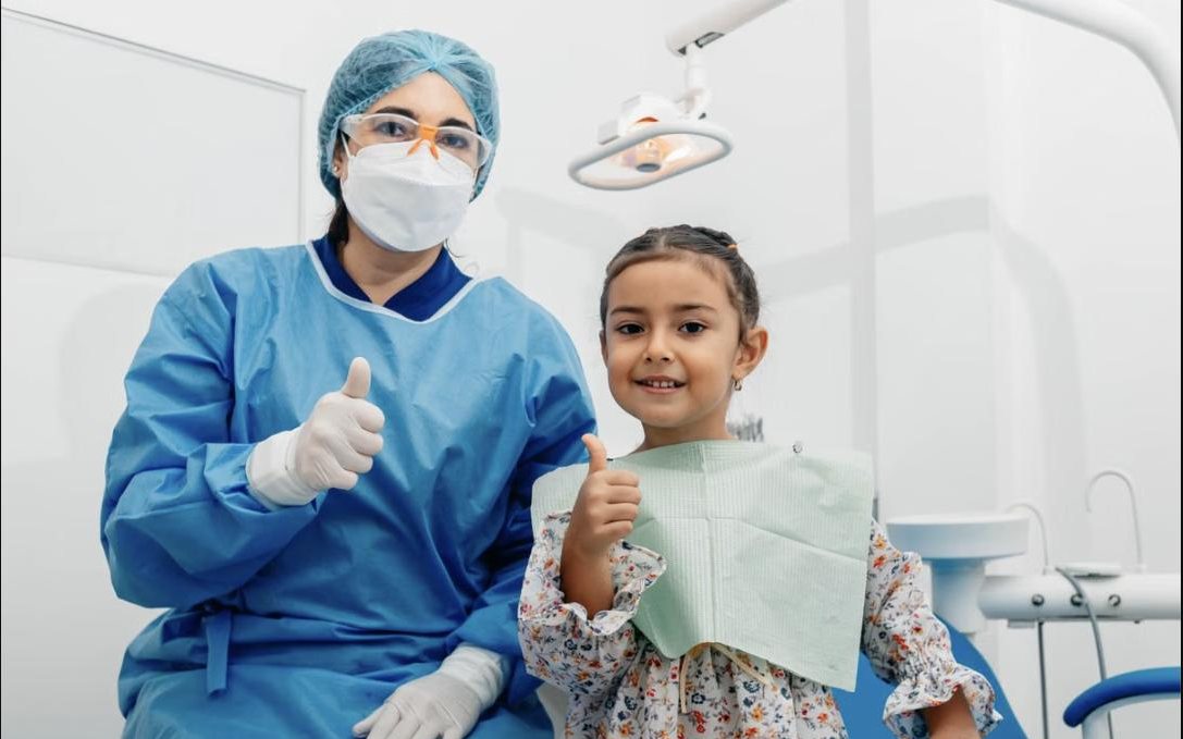 Young patient giving a thumbs up with her dentist